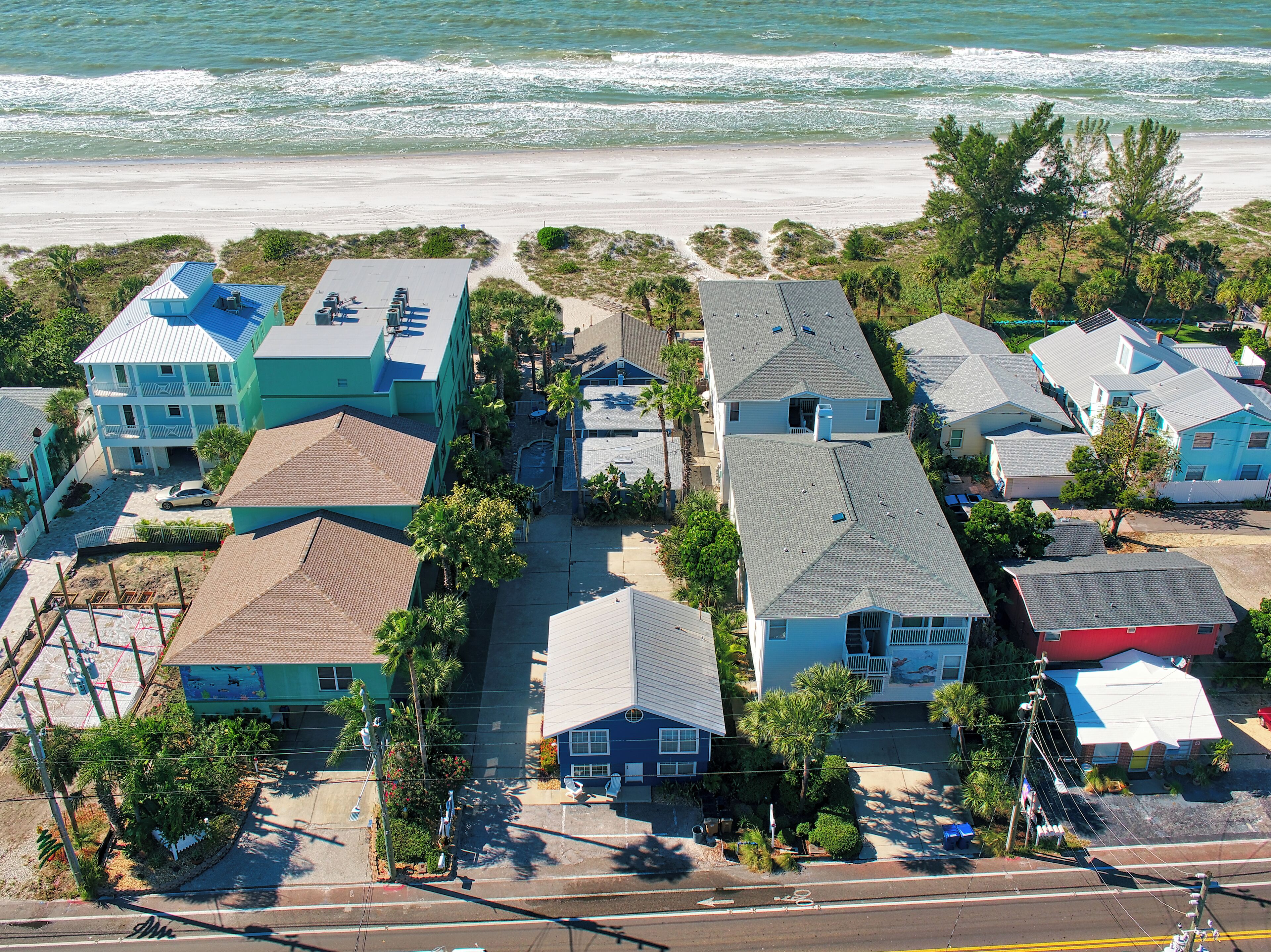 A coastal residential area with houses, some with blue roofs, and a beach in the background.