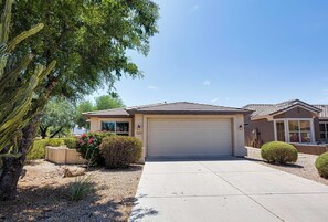 A residential house with a garage, a driveway, and a well-maintained garden with a cactus and shrubs.