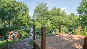 A wooden deck with a rope barrier, surrounded by lush green trees.
