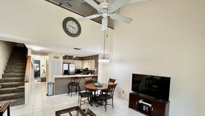 A spacious living room with a dining area, kitchen, and a staircase leading to another level. - Relax and enjoy your tropical getaway in this lovely Silver-rated condo! (Saint Augustine)