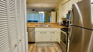 Una cocina con refrigerador de acero inoxidable, lavavajillas y horno doble. Cuenta con encimera de madera y un lavamanos con grifo.