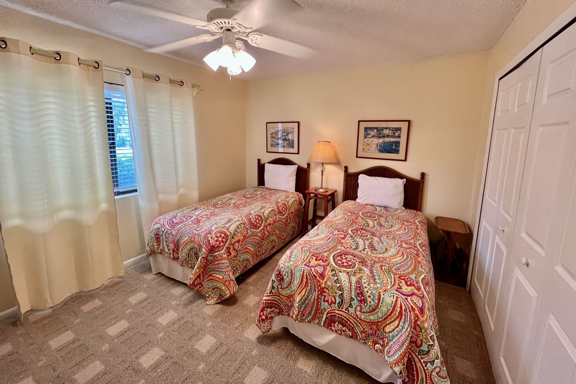 A bedroom with two beds, a ceiling fan, and two bedside lamps.