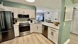 Una cocina moderna con armarios blancos, electrodomésticos de acero inoxidable y una pared verde claro.