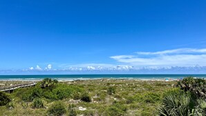 Un paisaje costero con cielo despejado, una playa y un paseo marítimo.