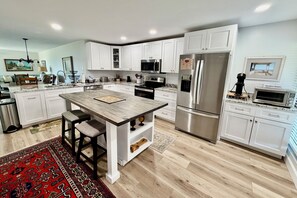 A modern kitchen with white cabinets, stainless steel appliances, and a central island with stools. - ENJOY FREE FUN in this welcoming unit with relaxing lagoon and ocean view. (Saint Augustine)