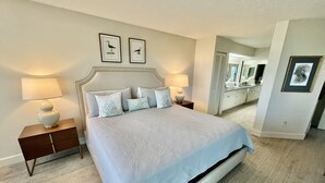 A neatly arranged bedroom with a large bed, two bedside tables with lamps, a dresser, and a mirror. - FREE FUN DAILY with this beautiful corner unit with substantial wrap around porch and marvelous views of the Atlantic Ocean! (St. Augustine)