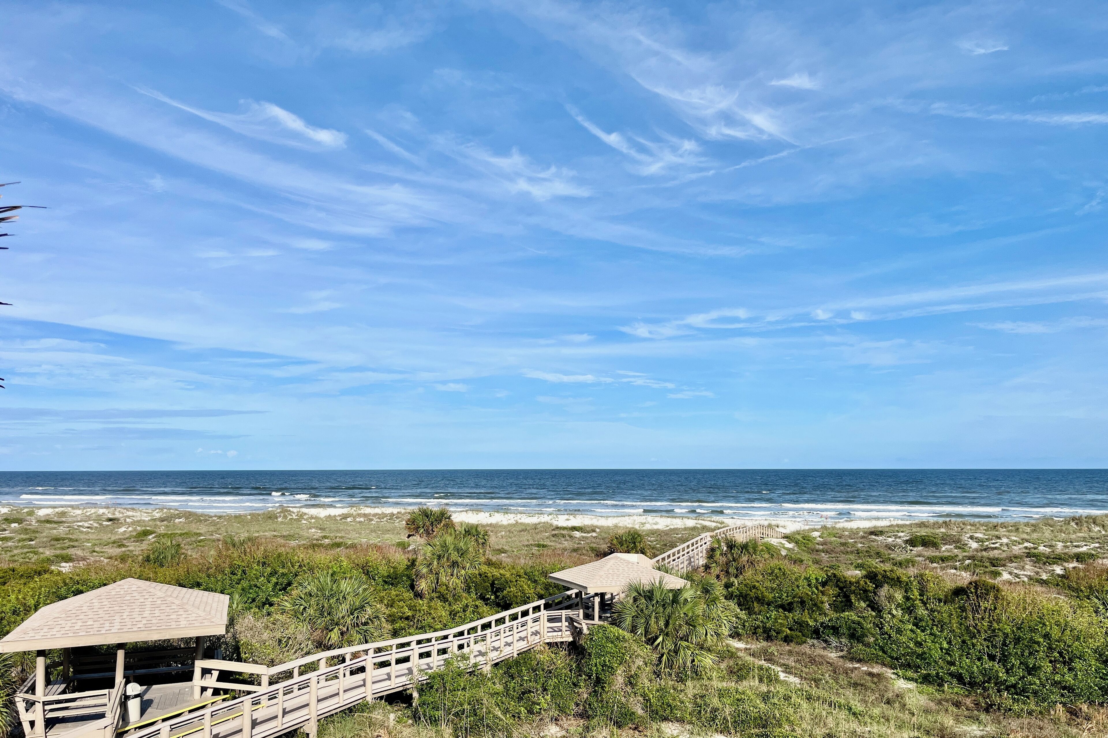 Une vue sur la plage avec une promenade en bois menant à un belvédère.