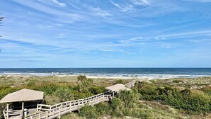 Vista sulla spiaggia con una passerella di legno che conduce a un gazebo.