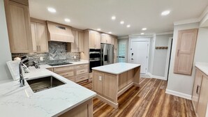 Una cocina moderna con armarios de madera, encimera de mármol y horno y refrigerador integrados.