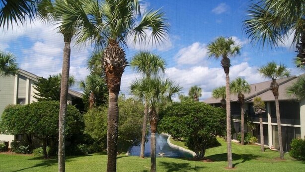 A landscaped area with palm trees, a water feature, and buildings with a modern design. - Enjoy your morning coffee on your covered lanai, then head over to beach only a brisk walk away! (Saint Augustine)