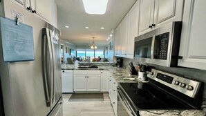 Una cocina moderna con electrodomésticos de acero inoxidable, armarios blancos y vistas al exterior.