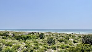 A coastal landscape with a beach, a wooden boardwalk, and dense greenery. - Spacious ocean front condo, perfect for sipping your morning coffee and enjoying the gentle waves! (Saint Augustine)