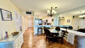 A spacious kitchen with a central island, wooden flooring, and a dining area with a round table and chairs. - Spacious ocean front condo, perfect for sipping your morning coffee and enjoying the gentle waves! (Saint Augustine)