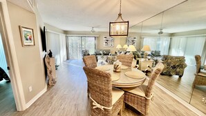 A dining area with wicker chairs, a round table, and a chandelier. - Comfortable Gold-rated condo perfect for the best vacation yet! (Saint Augustine)