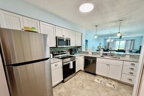 A modern kitchen with stainless steel appliances, white cabinetry, and a patterned floor.