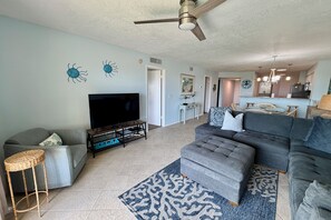 A living room with a sofa, TV, and a ceiling fan.
