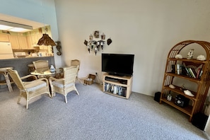 A living room with a TV, bookshelf, and wicker furniture.