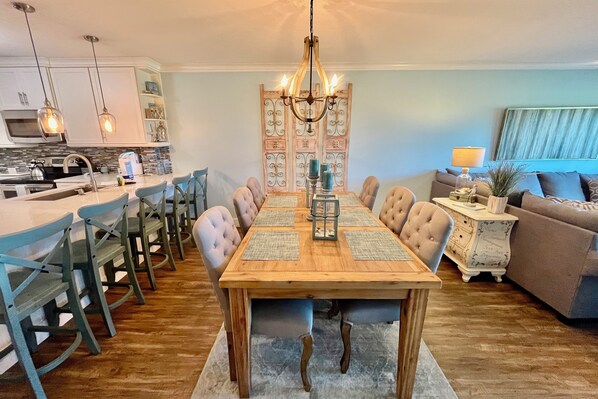Un coin repas avec une table en bois, des chaises bleues et un lustre.