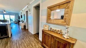 Una cocina moderna con piso de madera, una isla integrada y un espejo grande sobre un mueble bajo de madera.