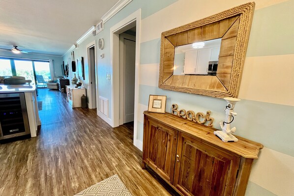 Una cocina moderna con piso de madera, una isla integrada y un espejo grande sobre un mueble bajo de madera.