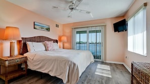A bedroom with a bed, two bedside lamps, a ceiling fan, a window with blinds, and a TV mounted on the wall. - Gulf Watch 216 - Anna Maria Island - Condo 2 Bedroom / 2 Bath Gulf to Bay access, maximum occupancy of 4 people . (Bradenton Beach)