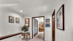 A hallway with framed pictures on the walls, a wooden bench, and a potted plant. - Lush View in Sunny Kona-Keauhou! Kitchen Ease, Lanai, Laundry, WiFi, TV Kanaloa 1204 (KAILUA-KONA)
