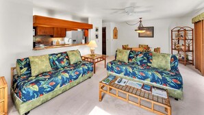 A living room with two sofas, a coffee table, and a dining area with a table and chairs. - Lush View in Sunny Kona-Keauhou! Kitchen Ease, Lanai, Laundry, WiFi, TV Kanaloa 1204 (KAILUA-KONA)