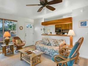 A living room with a ceiling fan, a sofa, two armchairs, a coffee table, and a television.