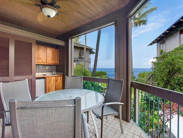 A balcony with a round table and chairs, overlooking a scenic ocean view.