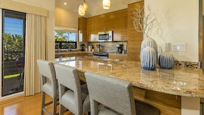 A modern kitchen with wooden cabinets, a granite countertop, and a large island with bar stools.