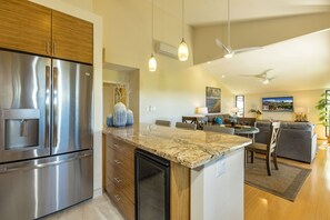 A modern kitchen with a stainless steel refrigerator, a built-in water dispenser, and a granite countertop.