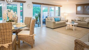 A spacious living room with a beige sofa, two wicker chairs, a glass coffee table, and a large window offering a view of the outdoors. - P43 - Spacious 3 bedroom 3 bath home with Pool in the Sombrero Beach Area (Marathon)
