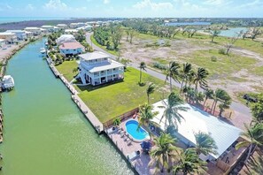 A resort with a swimming pool, a dock with boats, and a view of the water.