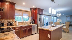 A modern kitchen with dark wood cabinets, stainless steel appliances, and a marble countertop. - P43 - Spacious 3 bedroom 3 bath home with Pool in the Sombrero Beach Area (Marathon)