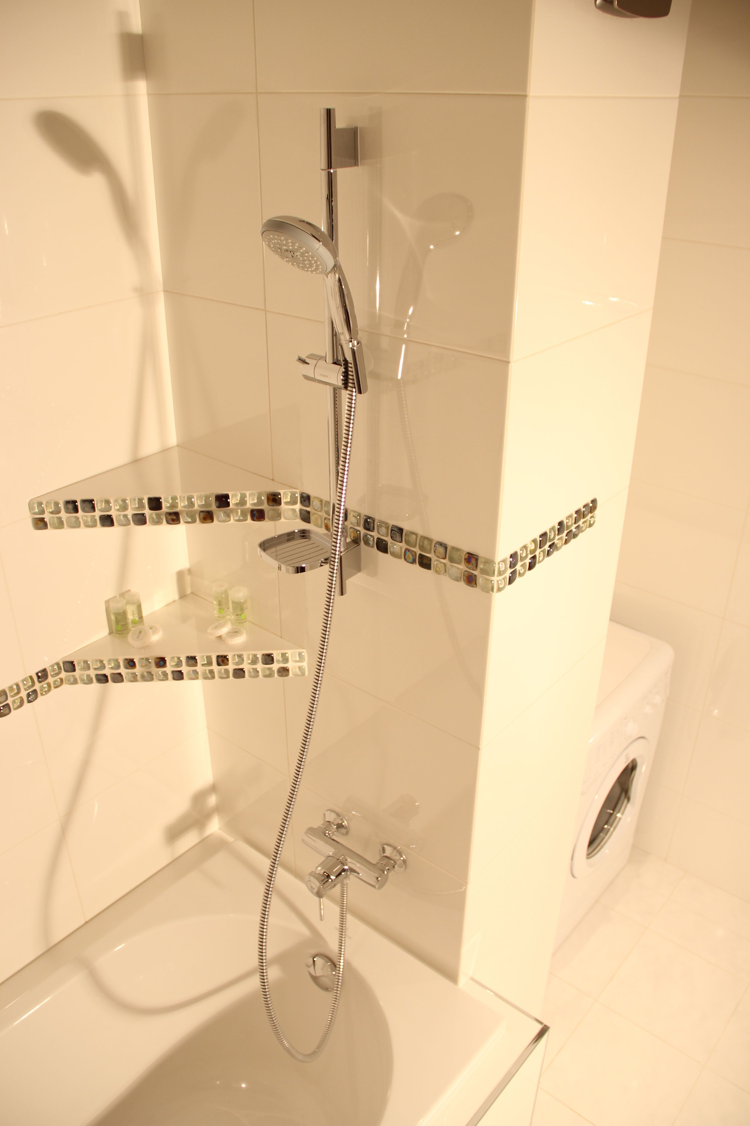 A modern bathroom with a glass shower enclosure, chrome fixtures, and decorative mosaic tiles.