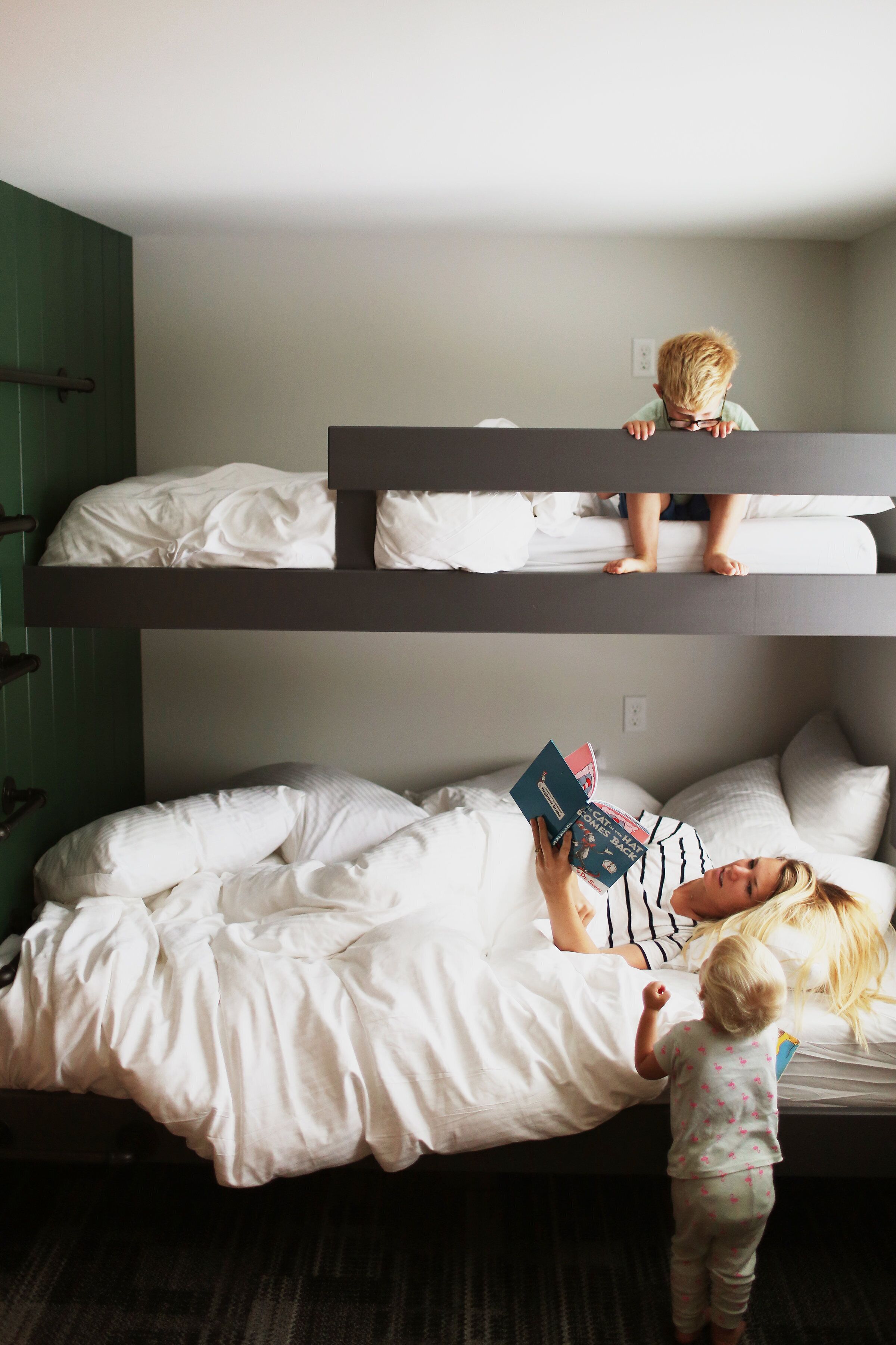 A bunk bed room with a person lying on the lower bunk and a child standing on the upper bunk.