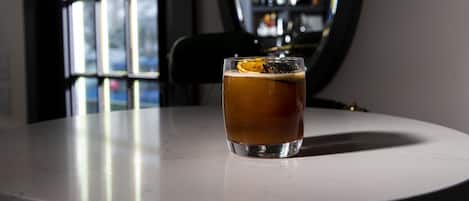 A glass of beer on a white table with a window in the background.