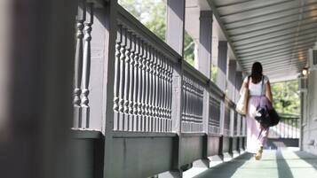 A covered walkway with a metal railing and a person walking away from the camera.