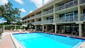 A hotel with a swimming pool, multiple balconies, and outdoor seating areas.