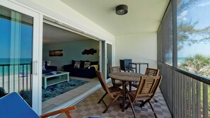 A balcony with a checkered floor, a wooden table with chairs, a sofa, and a coffee table. - Sunset Terrace 203  - Anna Maria Island - Beach front condo 2 Bedroom/ 2 Bath Bradenton Beach, Anna Maria Island, maximum occupancy of 4 people. (Bradenton Beach)