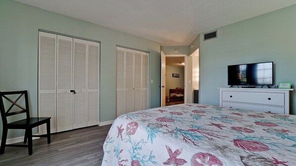A bedroom with a bed, a TV, a dresser, and two closets.