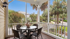 A covered outdoor area with a round table and four chairs, surrounded by a white railing, overlooking a well-maintained garden with palm trees and a clear blue sky. - Screened porches, decks, rockers, hammocks and an upstairs balcony with ocean views (Boquete)