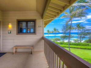 Enjoy the ocean view from this hotel's balcony, featuring a bench and railing, with palm trees and the sea in sight.