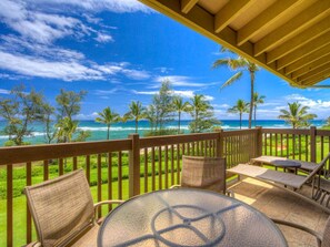 Relax in a serene oceanfront setting with a seating area, wicker chairs, and a glass table.