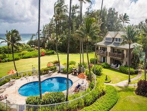 A resort with a swimming pool, outdoor seating, and a view of the ocean.
