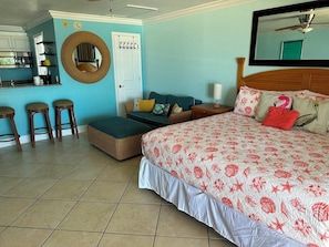 A bedroom with a bed, a sofa, a small dining area, and a bathroom.