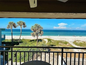 A balcony with a view of a beach, palm trees, and the ocean.