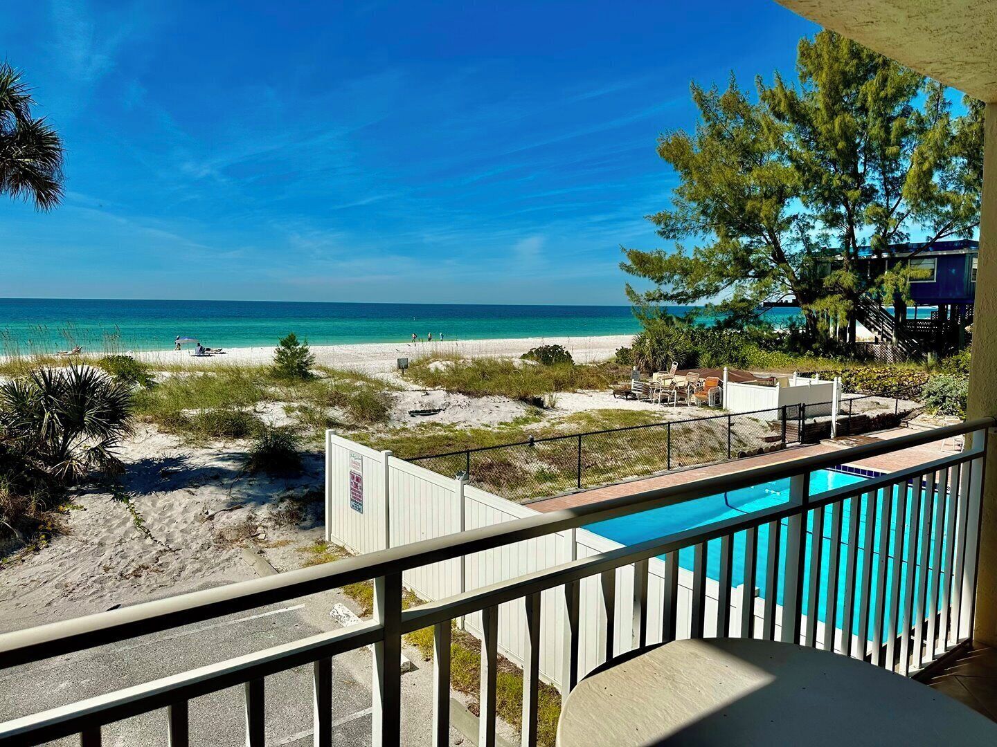 A beach view from a balcony with a pool.