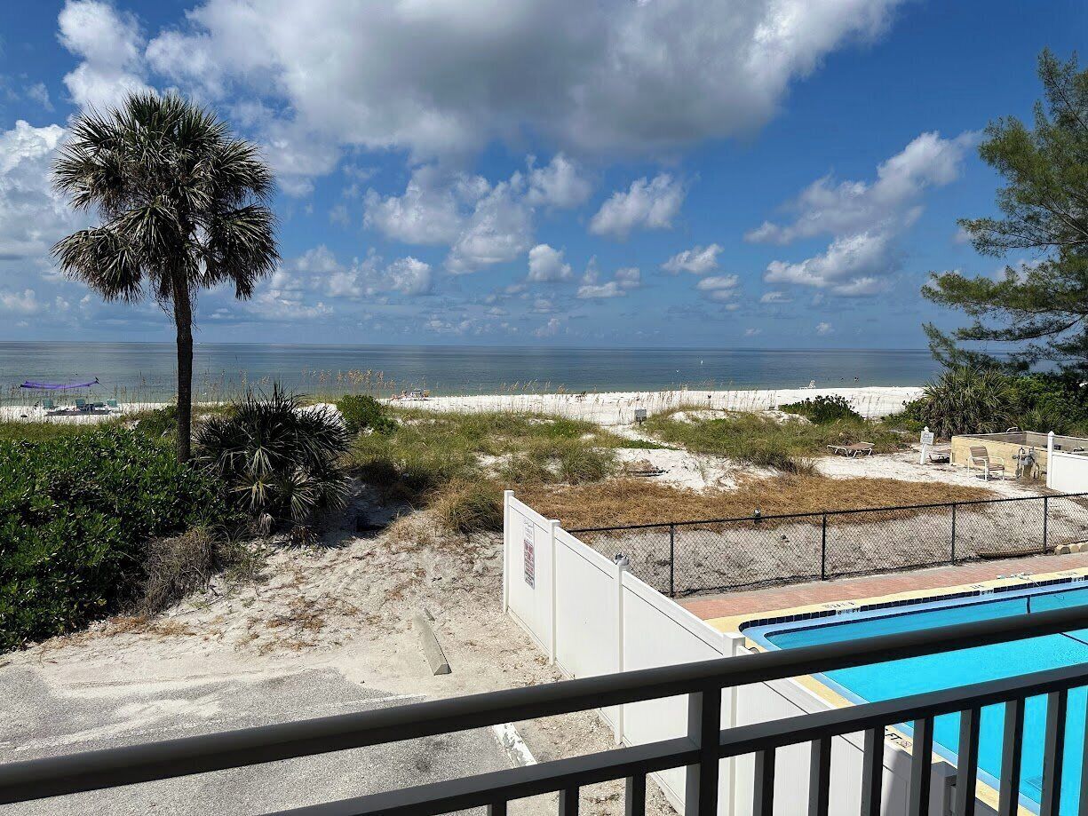A pool area with a view of the beach and ocean.