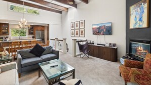 A spacious living room with a fireplace, a dining area, and a kitchen with wooden beams. - Riverside Condo with Mountain and Town views and updated furnishings. (Telluride)